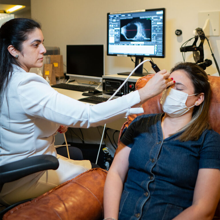 Médico oftalmologista realizando exame ocular em paciente.